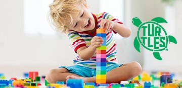a young child plays with a block of toys; turtles program registered logo