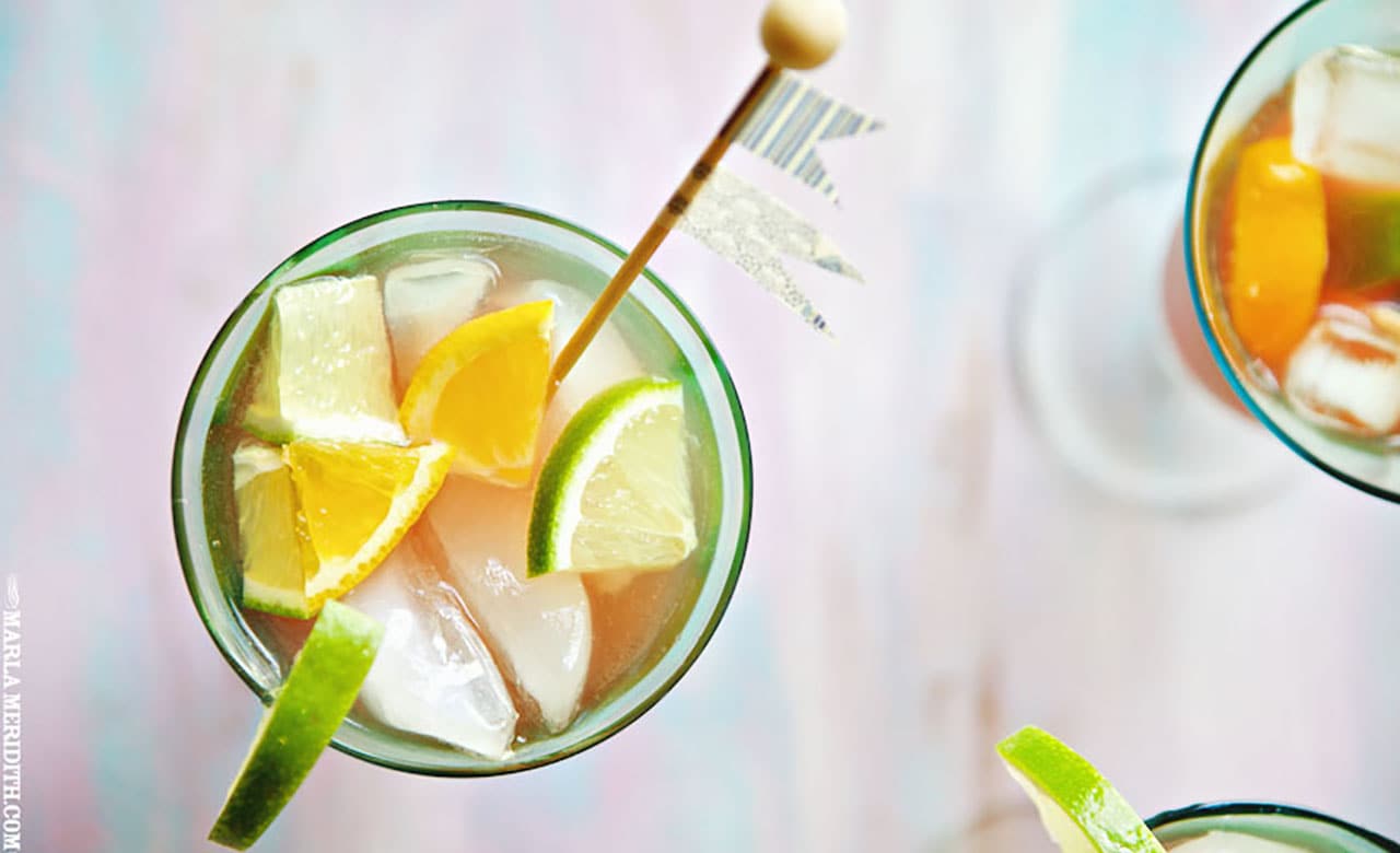 Looking down at a glass filled with ice and citrus with a wooden decoration