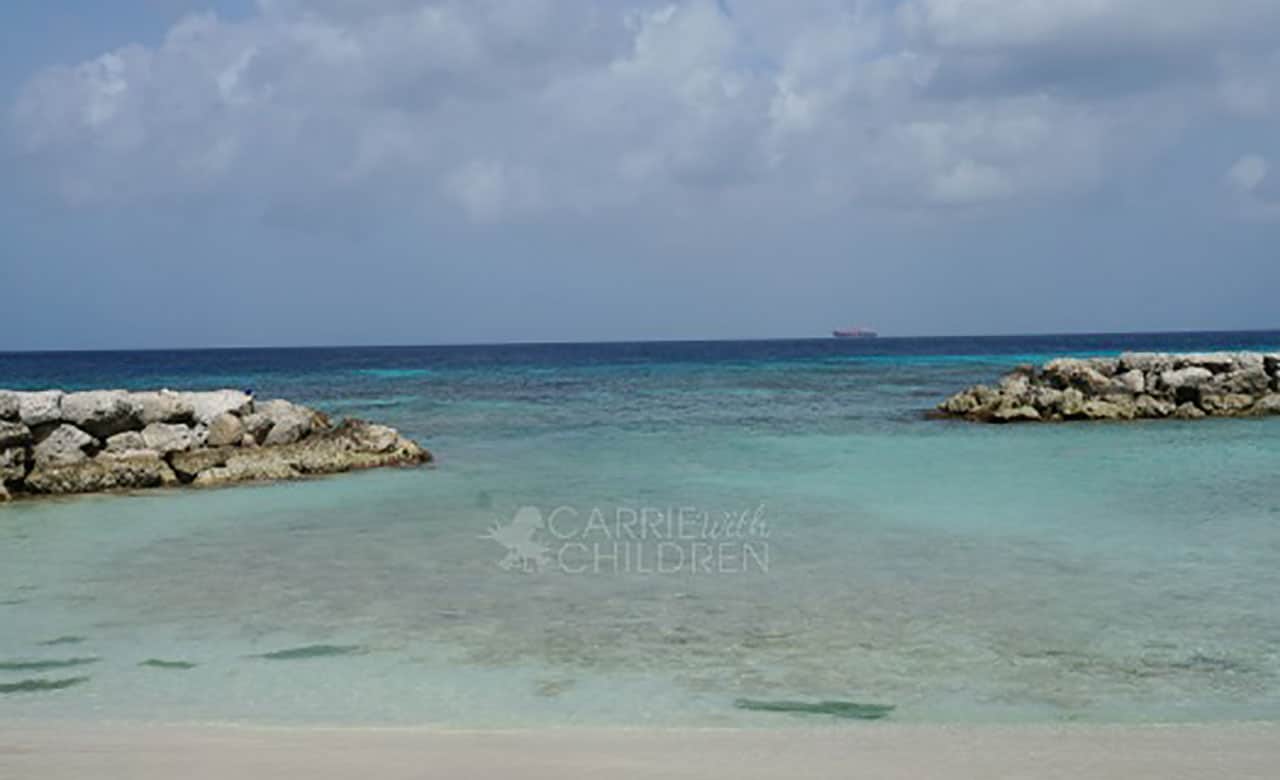 Rocky beach with cruise ship in distant background – Carrie with Children watermark