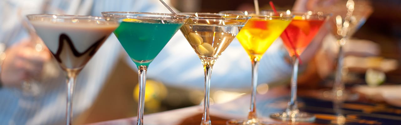 Five uniquely filled martini glasses sitting at a bar