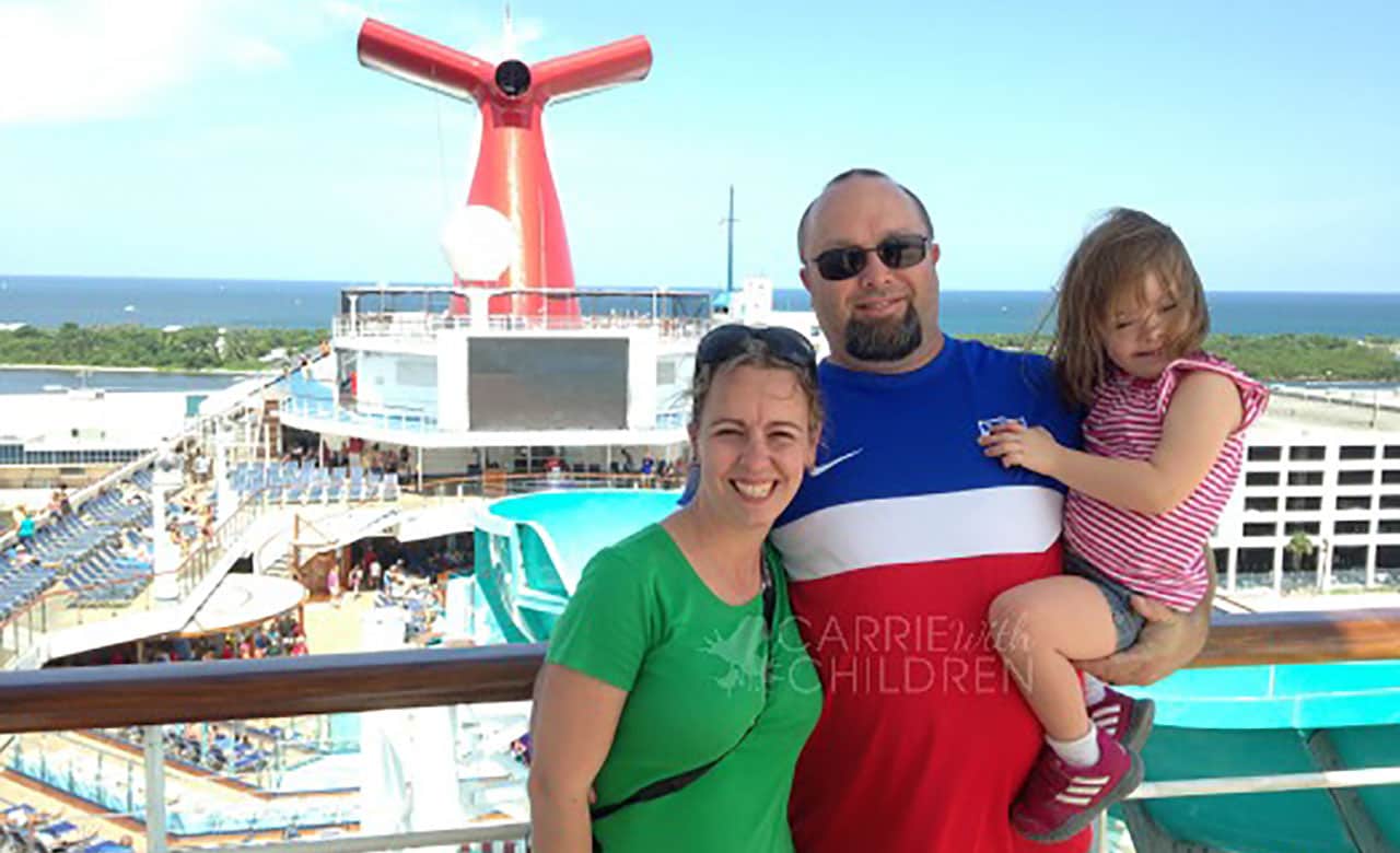 Woman, man and child pose for picture overlooking a carnival ship deck