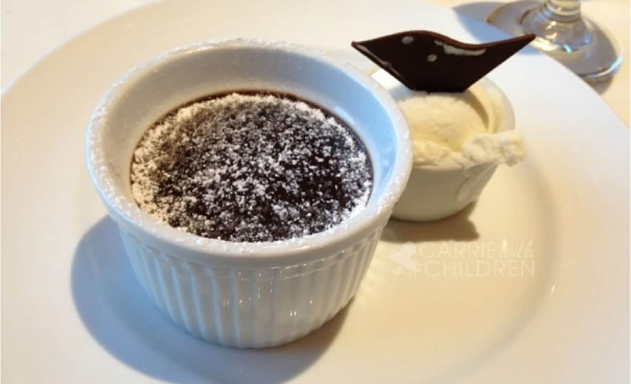 A ramekin filled with a warm chocolate melting cake and side of ice cream