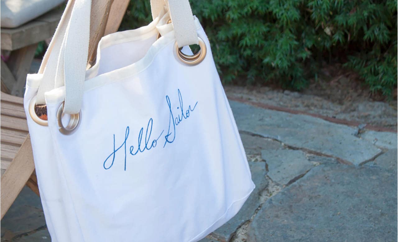 Canvas handbag with text "hello sailor" draped over a chair