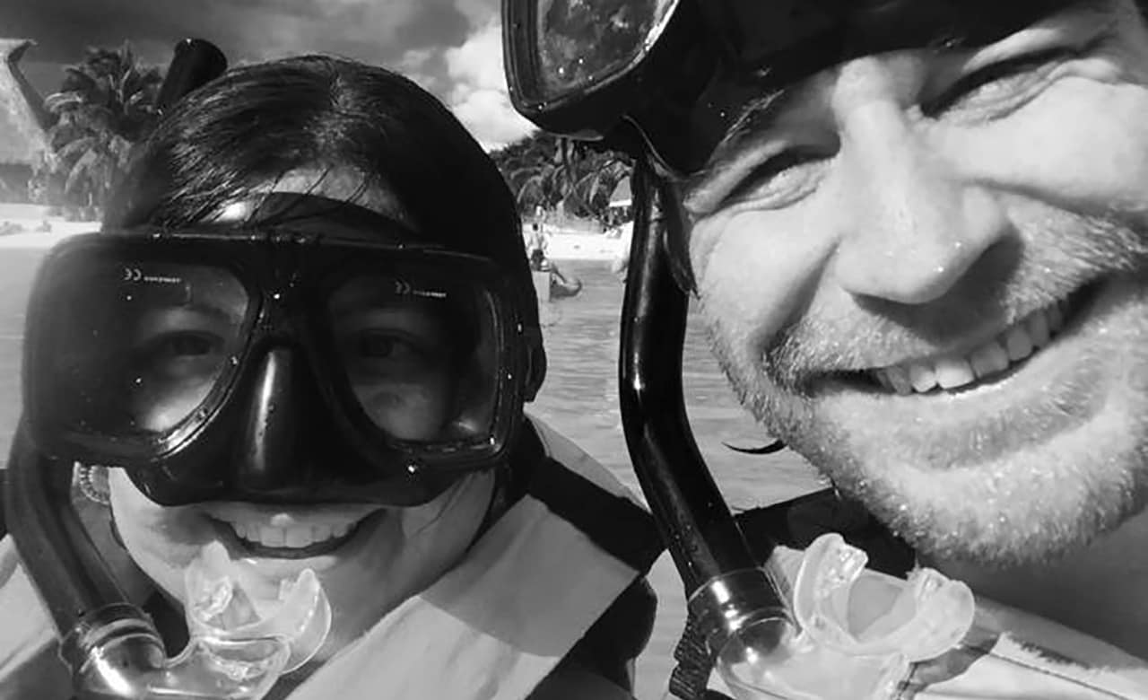 A black and white photo of a man and woman smiling wearing goggles and snorkels