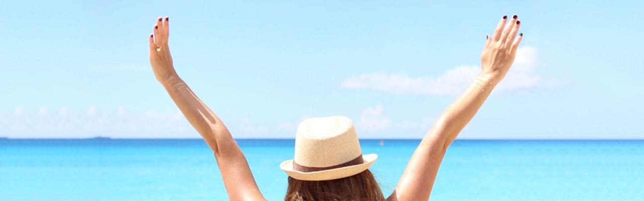 Woman with arms in air looking at sea