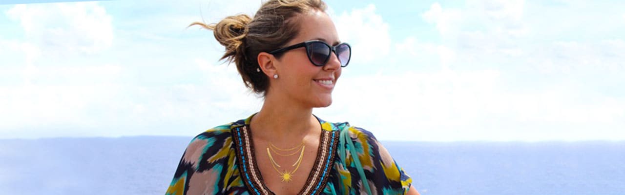 Woman standing on deck with sunglasses and hair bun on carnival ship