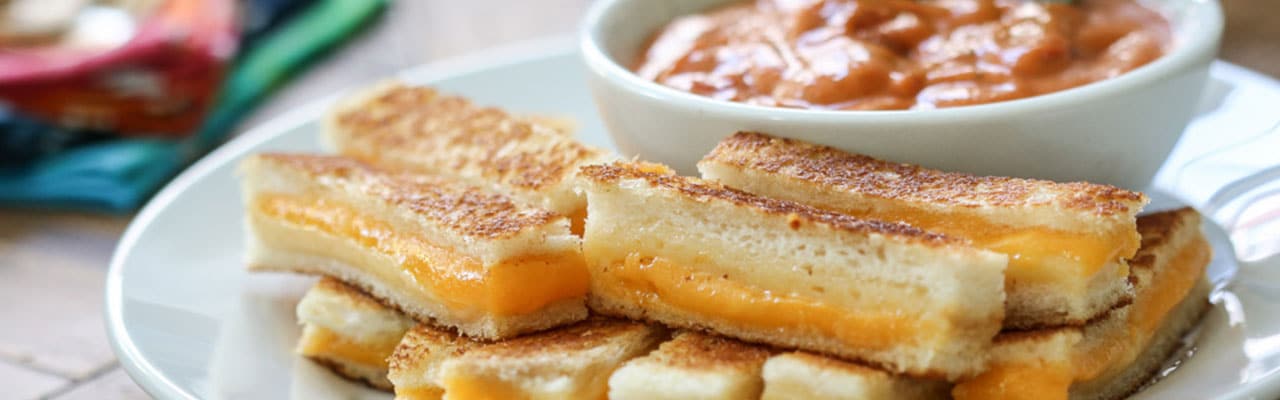 Plate of long grilled cheese slices and bowl of tomato soup