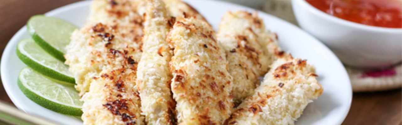 A plate of long, browned strips of chicken slices of lime on the side