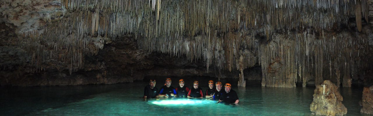 A group of people standing in a pool of water in a cave