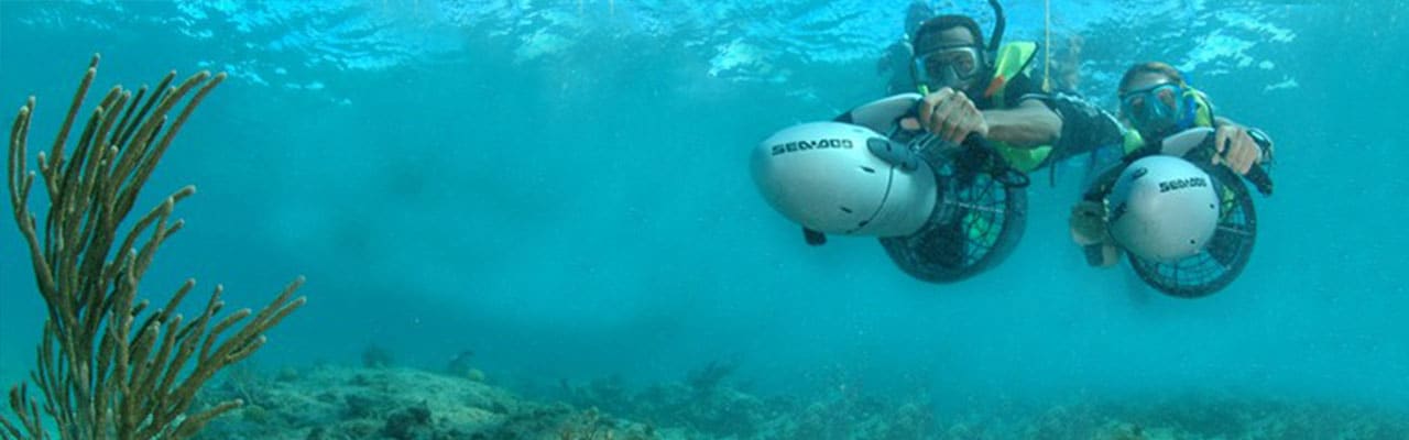 Two people underwater with handheld propellers in the caribbean
