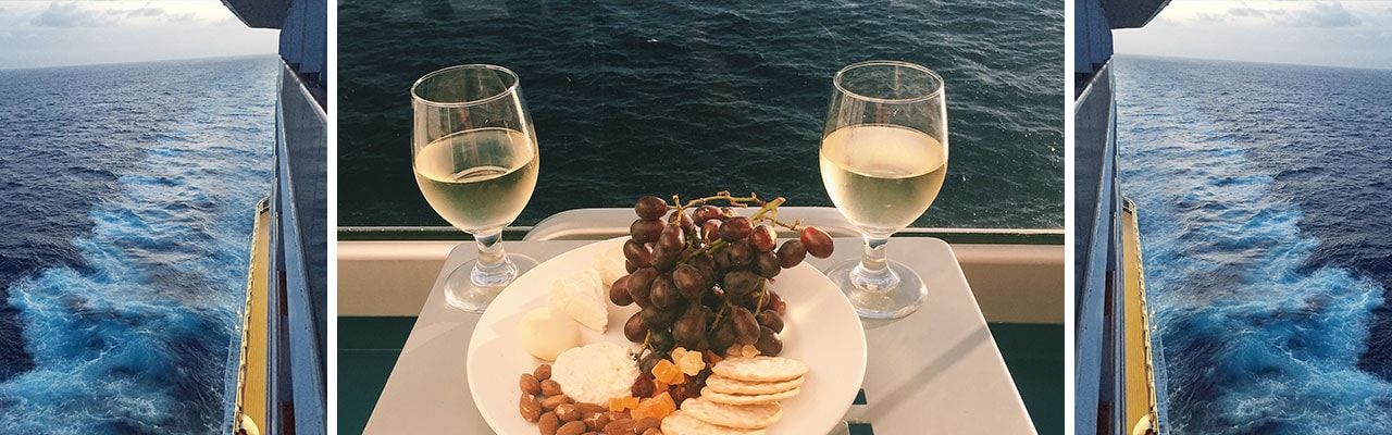 Fruit and Cheese plate and wine in-between two photos of a ship's wake at sea