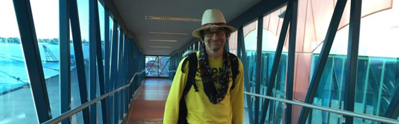 Man walking down a window-lined hallway onto carnival ship