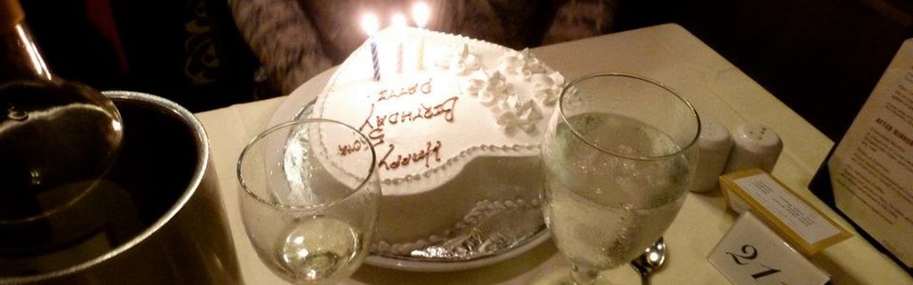 A white heart-shaped cake with lit candles at a resturant table