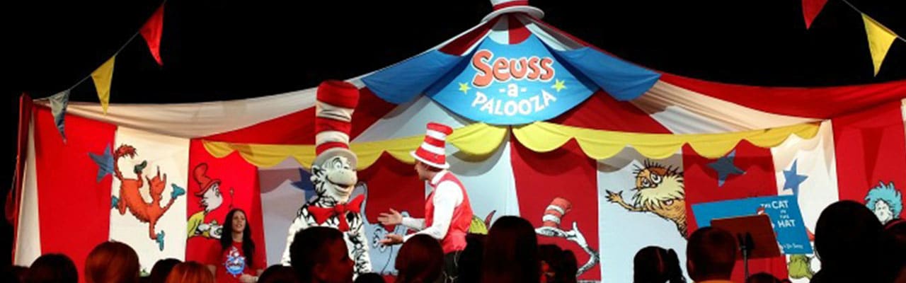 Costumed Cat in the Hat on stage with two performers on carnival ship