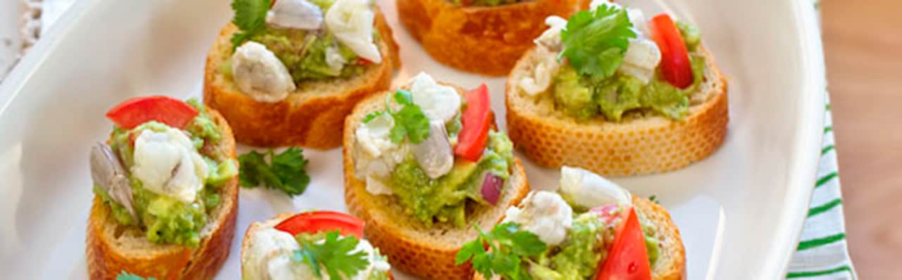 closeup of Plate with small bread slices topped with tomato and avocado