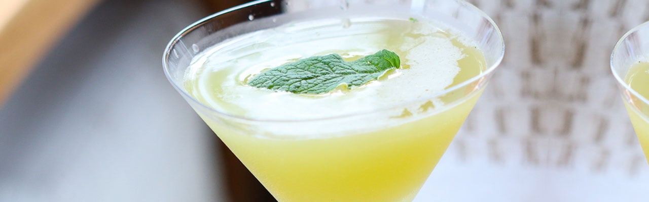 filled martini glass with a basil leaf floating in center