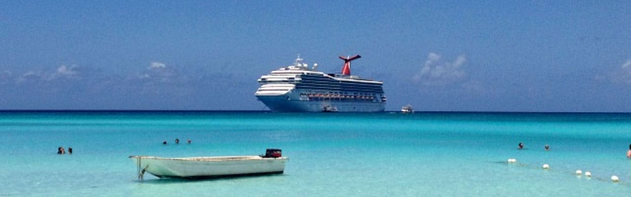 small boat near beach and cruise ship in distance