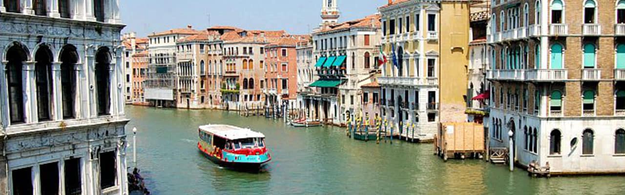 Small boat going through a building-lined canal in Italy