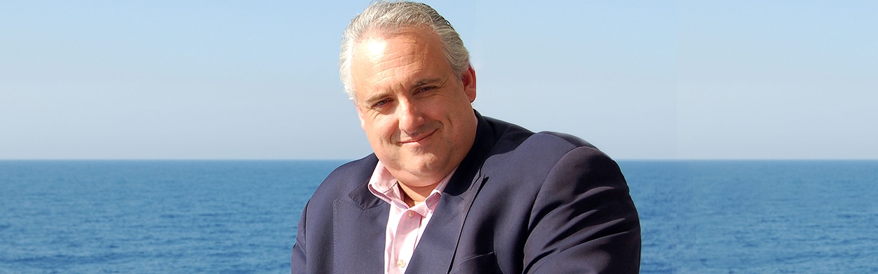 Banner with image of man smiling with the blue ocean behind him