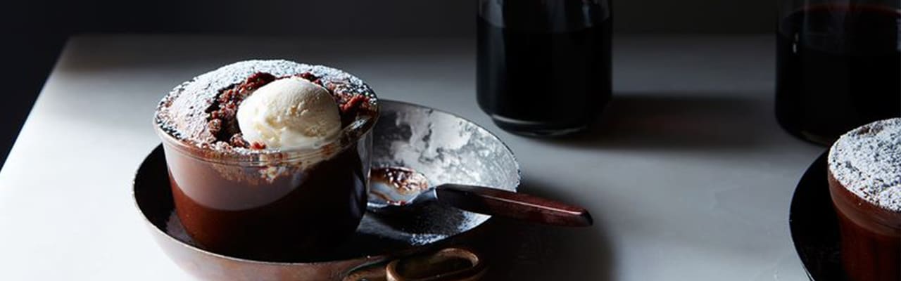 warm chocolate melting cake with vanilla ice cream scoop in glass dish placed on copper skillet
