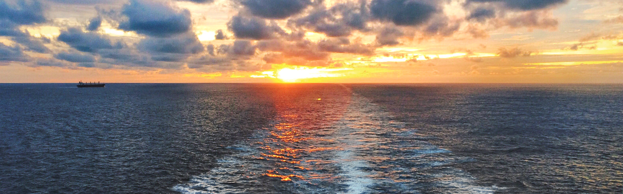 sunset view of ocean horizon over wake of ship