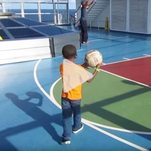 little boy gets ready to take a shot at a basketball hoop onboard a Carnival cruise, link to Youtube video