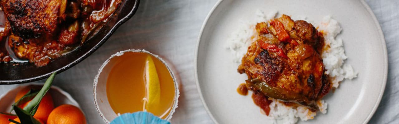 Banner image of pollo guisado chicken dish and a citrus rum spritzer