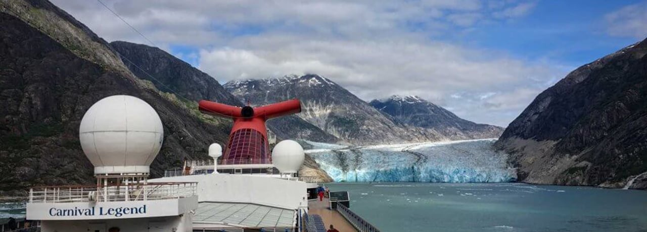 A view from the front of the Carnival Legend ship looking behind at a glacier