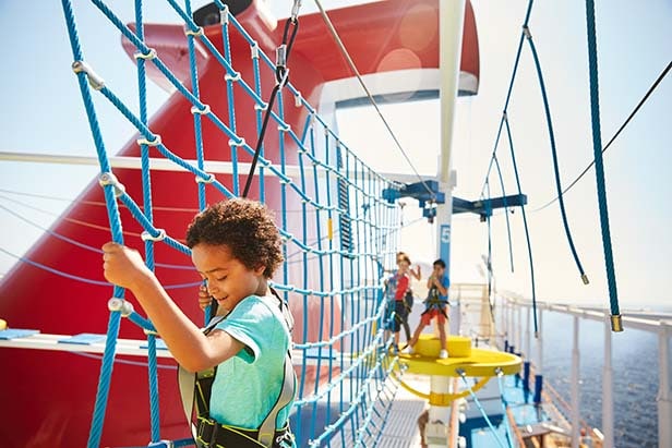young boy climbing the rope bridge on the ropes course