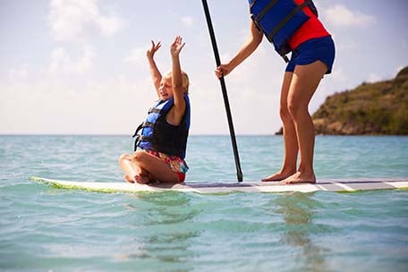 little girl with a big smile and arms up on paddleboard