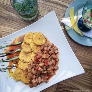 Dominican–style conch with tostones served on a white plate