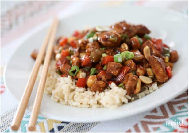 Kung Pao Chicken over rice with two chopsticks on the side of the plate