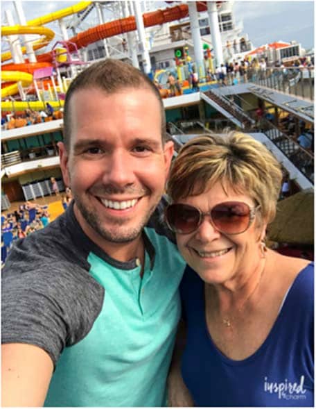 Michael and his mother smiling with the Carnival Vista waterslides behind
