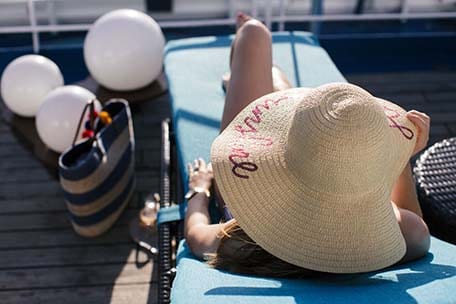 Overhead photo of Caroline sitting in a lounge chair and wearing a sun hat