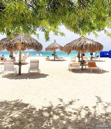 White sand beach with little huts and chairs set up in Aruba