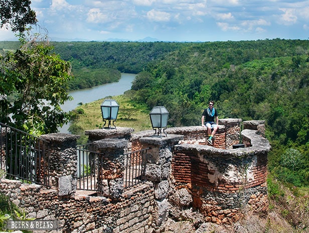 Randy sitting on a wall in La Romana with trees and Chavon River behind him in the distance