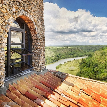 Photo of stone building with a stucco roof and Chavon River in the distance