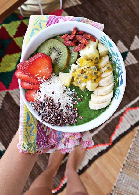 Hand holding out colorful cloth napkin and green smoothie bowl