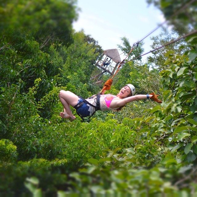 woman ziplining through the trees in mexico