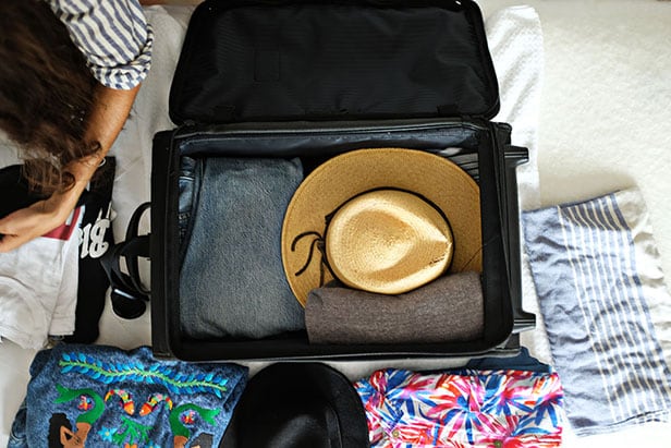 Overhead photo of of suitcase with stack of hats inside
