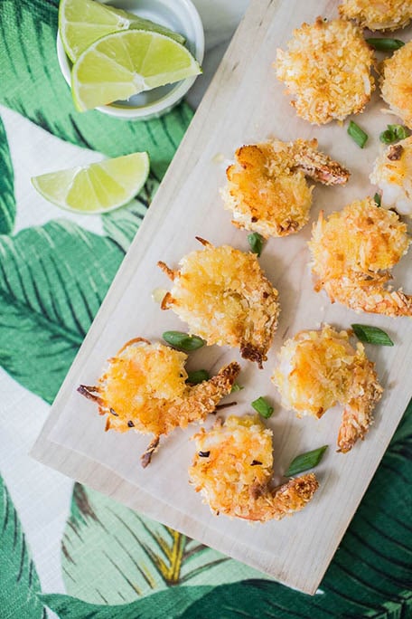 Coconut shrimp on kitchen counter with dipping sauces and limes