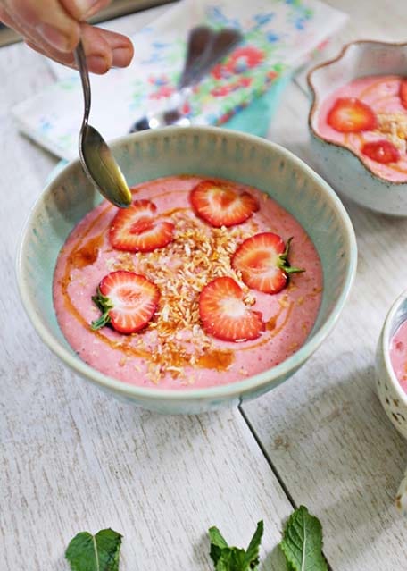 Close up of strawberry coconut soup with spoon drizzling coconut nectar