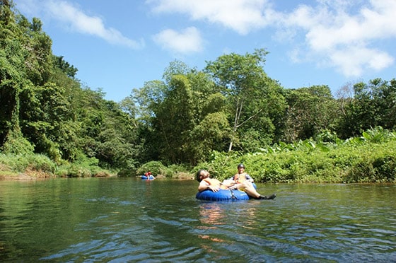 two men enjoy river tubing along the calm river in dominica