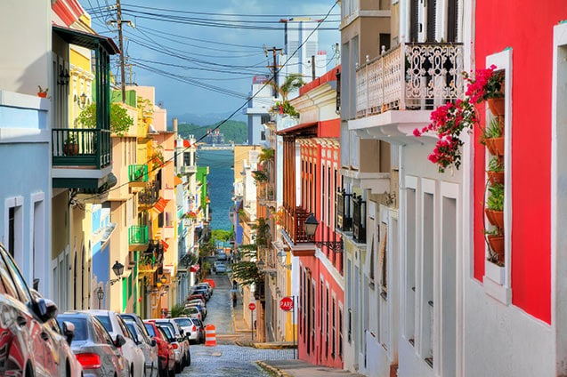 small block of colorful houses along a street in old san juan that leads straight to the ocean