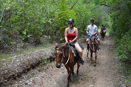 people horseback riding through a dirt trail in st lucia