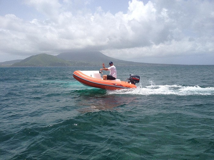 man waving as he speeds on a mini speedboat of the coast of st kitts