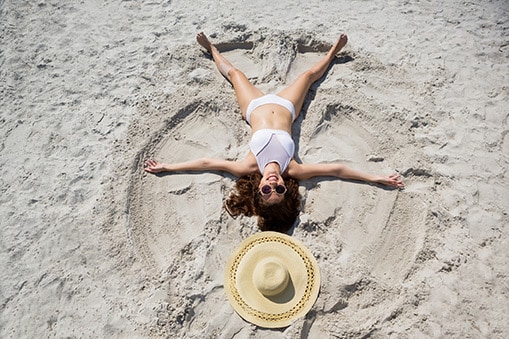 woman making a snow angel in the sand