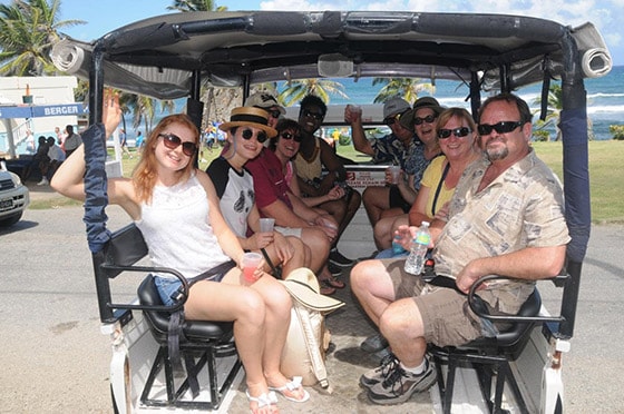 people sitting on the back of a 4x4 truck before a tour of barbados