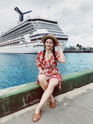Noelle sitting on pier in front of Carnival ship