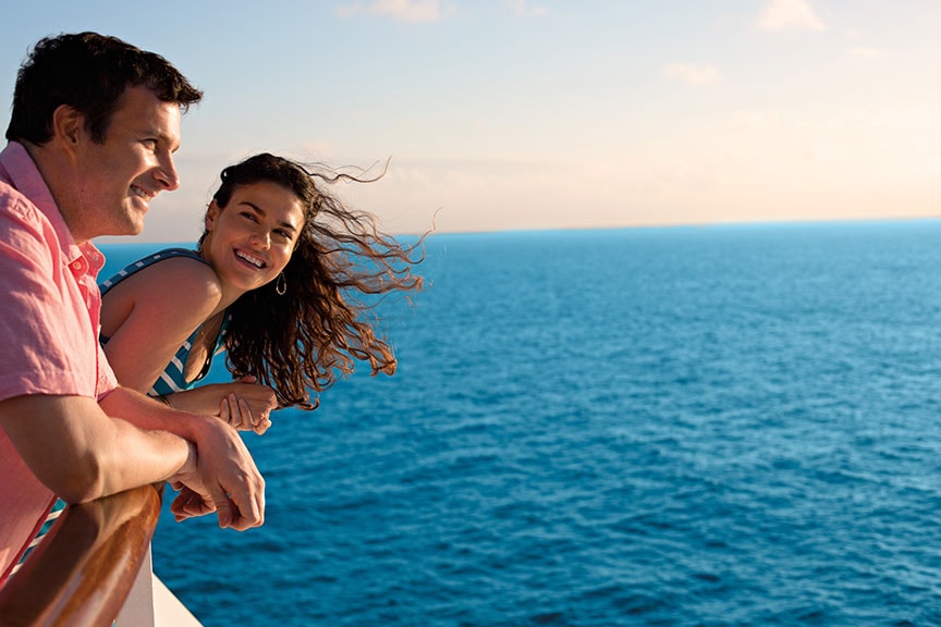woman looks at man as he stares out to the ocean onboard a cruise